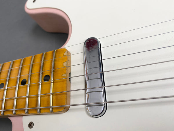 Close-up of vintage electric guitar neck with maple fretboard and chrome pickup on white body with pink accents and six metal strings