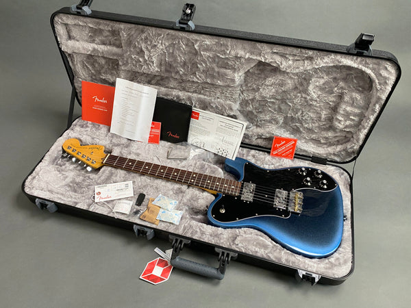 Fender electric guitar in blue burst finish with black pickguard inside a plush gray hard shell case, including Fender documentation and accessories