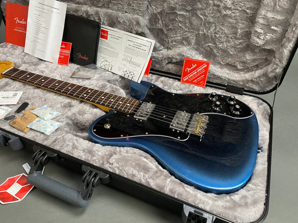 Fender electric guitar in blue burst finish with rosewood fretboard and dual humbucker pickups in a hardshell case with Fender setup and warranty documents, included tools, and Friedrich Cozy plush interior lining for protection.