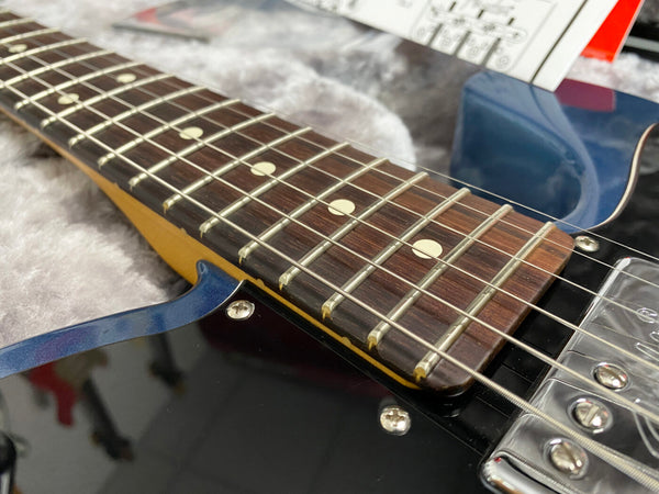 Close-up of electric guitar rosewood fretboard with dot inlays and metal frets on blue and black body with chrome pickups and screws