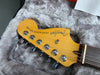 Close-up of Fender Telecaster Deluxe electric guitar headstock with tuning pegs and strings resting on a plush gray guitar case interior