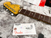 Fender Telecaster Deluxe electric guitar headstock and rosewood fretboard with Fender inspection tag on gray plush surface