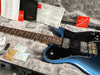 Fender electric guitar in blue burst finish with black pickguard, rosewood fretboard, and dual humbucker pickups displayed in gray plush guitar case with Fender manuals and accessories