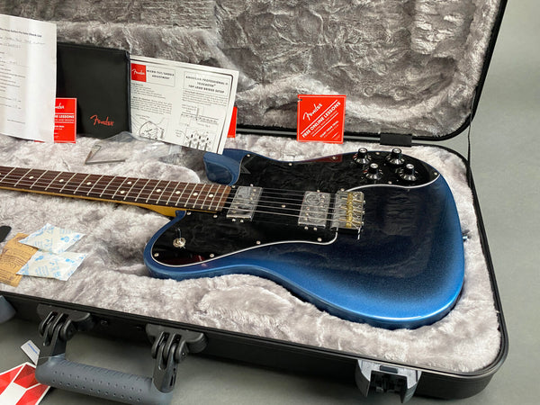 Fender electric guitar with metallic blue finish and black pickguard in a plush gray guitar case with Fender manuals and accessories