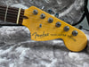 Close-up of Fender Telecaster Deluxe electric guitar headstock with chrome tuning pegs on gray plush guitar case lining