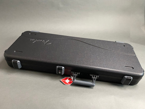 Closed black Fender hard guitar case with silver latches and handle on gray background, TSA lock and red travel tag visible