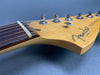 Close-up of Fender Telecaster electric guitar headstock with tuning pegs and strings on gray background