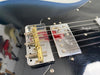 Close-up of black electric guitar bridge and chrome Fender pickup with strings and screws visible