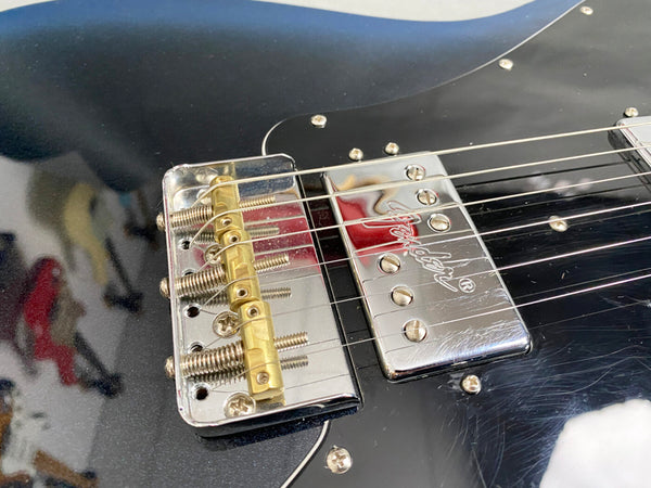 Close-up of black electric guitar bridge and chrome Fender pickup with strings and screws visible