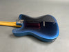 Back of electric guitar with metallic blue finish and maple neck on gray background
