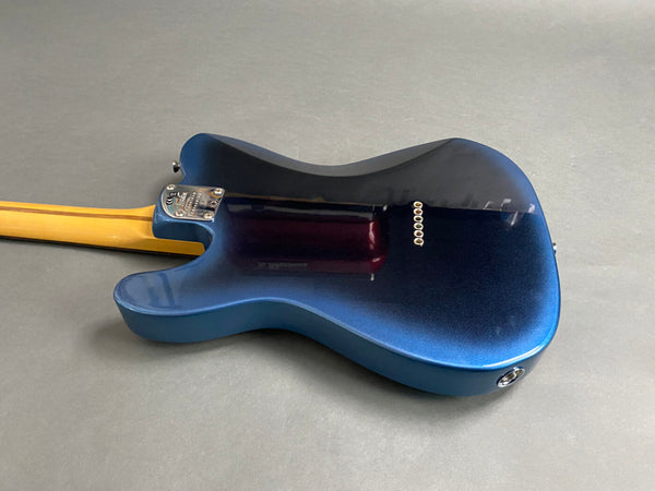 Back of electric guitar with metallic blue finish and maple neck on gray background