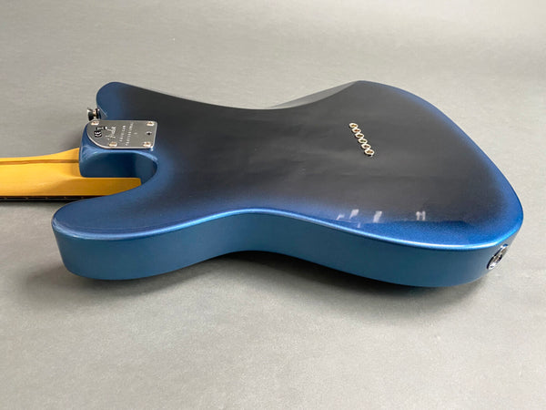 Back view of blue electric guitar body with visible string ferrules and neck joint plate on grey background