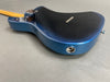 Back side view of electric guitar with metallic blue finish, bolt-on maple neck, and chrome input jack on gray background