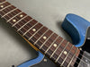 Close-up of electric guitar neck with rosewood fretboard and dot inlays on blue guitar body