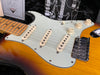 Close-up of Fender Stratocaster electric guitar in sunburst finish showing pickups, tone and volume knobs, and bridge