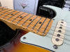 Close-up image of maple fretboard and single-coil pickup on a sunburst Fender electric guitar with vintage-style pickguard