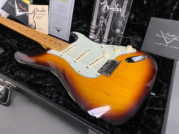 Fender Custom Shop sunburst electric guitar with maple neck and vintage-style tremolo bridge in a black plush-lined case with Fender care manuals and certificates