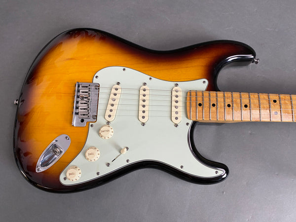 Sunburst electric guitar with white pickguard and maple fretboard on gray background