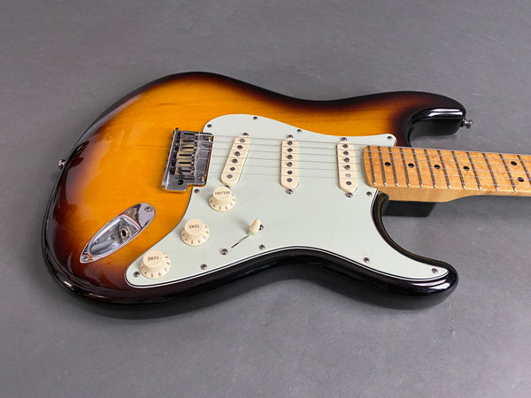 Sunburst electric guitar with white pickguard and maple fretboard on gray background