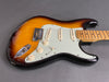 Electric guitar with sunburst finish, white pickguard, and maple neck on gray background