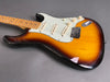 Sunburst electric guitar with maple neck and white pickguard on gray background, featuring three single-coil pickups and vintage-style knobs.