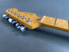 Close-up view of Fender electric guitar headstock with chrome tuning pegs and maple neck on gray background