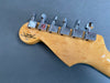 Close-up of Fender Custom Shop electric guitar headstock with chrome tuning pegs on a gray background