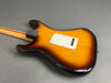 Back view of sunburst electric guitar with maple neck and white backplate on gray background