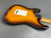 Back side of sunburst electric guitar body with white plastic cover and maple neck on gray background