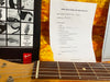 Close-up of Fender guitar neck showing frets and strings with Coffee House Guitars pre-sales checklist and Fender owner's manual in yellow plush guitar case interior.
