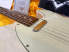 Close-up of white Fender Telecaster electric guitar body and rosewood fingerboard with vintage-style single coil pickup and certificate in plush yellow guitar case interior