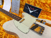 Close-up of a vintage Fender Telecaster electric guitar with white cracked finish, rosewood fretboard, and single-coil pickups, resting on a yellow plush case interior with accompanying Fender Custom Shop certificate and documentation.