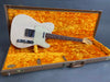 Vintage white Fender Telecaster electric guitar with maple neck and rosewood fretboard, displayed inside brown hard case with bright orange plush interior lining