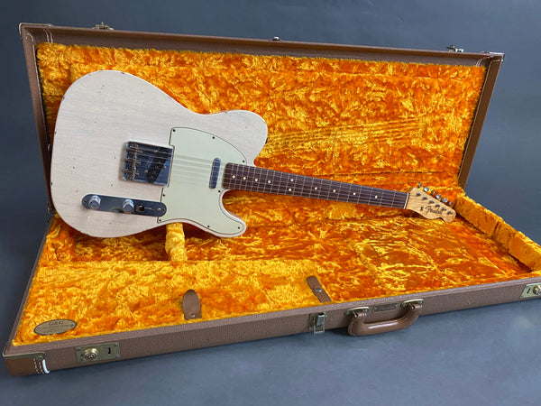 Vintage white Fender Telecaster electric guitar with maple neck and rosewood fretboard, displayed inside brown hard case with bright orange plush interior lining