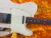 Close-up of vintage white electric guitar body and neck with rosewood fretboard on orange plush case interior