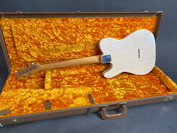 Electric guitar with white distressed finish inside a vintage orange plush-lined brown hardshell guitar case showing back view