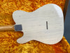 Vintage white electric guitar body with aged finish and string ferrules, displayed in a plush orange guitar case interior.