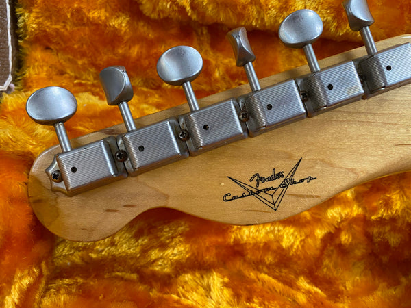 Close-up of vintage Fender Custom Shop electric guitar headstock with six tuning pegs on orange plush case interior