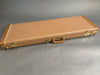Vintage brown hardshell guitar case with leather handle and brass latches on gray background