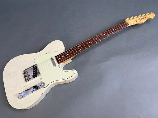 Fender Telecaster electric guitar with white finish, rosewood fretboard, vintage wear, and chrome hardware on gray background.