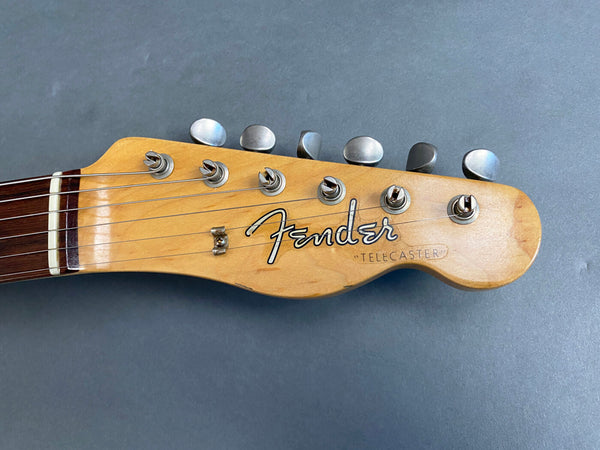 Close-up of vintage Fender Telecaster guitar headstock with tuning pegs and strings on gray background