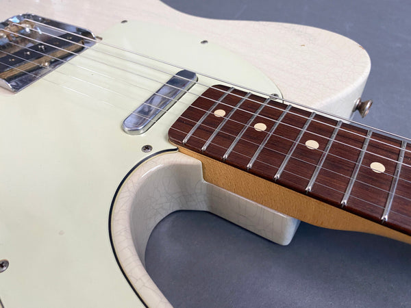 Close-up of vintage cream electric guitar body and rosewood fretboard with metal pickups and aged finish detailing