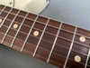 Close-up of guitar fretboard with metal frets, dot inlays, and steel strings on a rosewood fingerboard