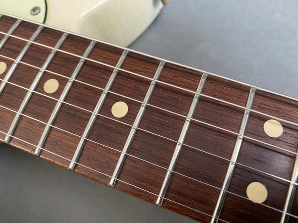 Close-up of guitar fretboard with metal frets, dot inlays, and steel strings on a rosewood fingerboard