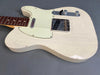 Close-up of vintage white solid body electric guitar with single-coil pickups and chrome hardware showing crackled finish and wear details