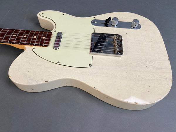 Close-up of vintage white solid body electric guitar with single-coil pickups and chrome hardware showing crackled finish and wear details