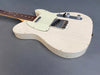 Vintage white electric guitar with worn distressed finish and rosewood fretboard on gray background