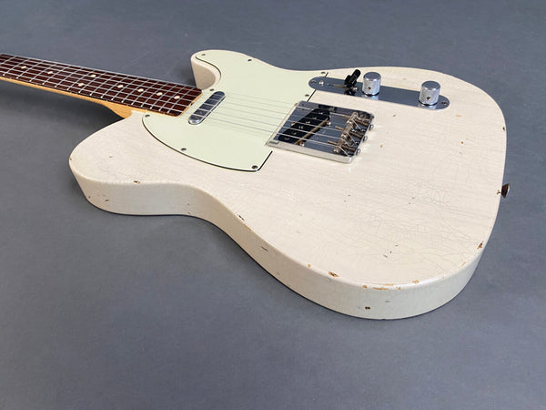 Vintage white electric guitar with worn distressed finish and rosewood fretboard on gray background