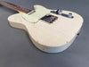 Vintage white electric guitar with relic finish and chrome hardware on gray background