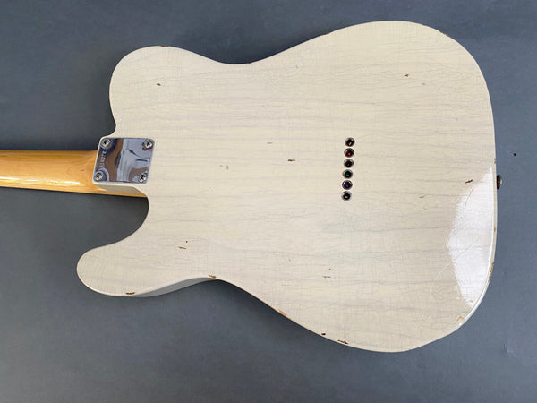Vintage white electric guitar body with string ferrules and neck plate, showing worn finish and aged cracks, on a dark background
